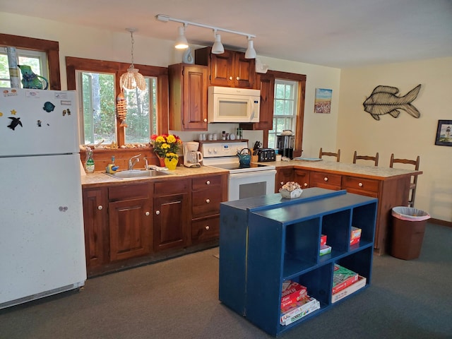 kitchen featuring white appliances, kitchen peninsula, sink, and hanging light fixtures