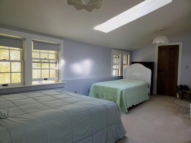 bedroom with vaulted ceiling with skylight and light carpet