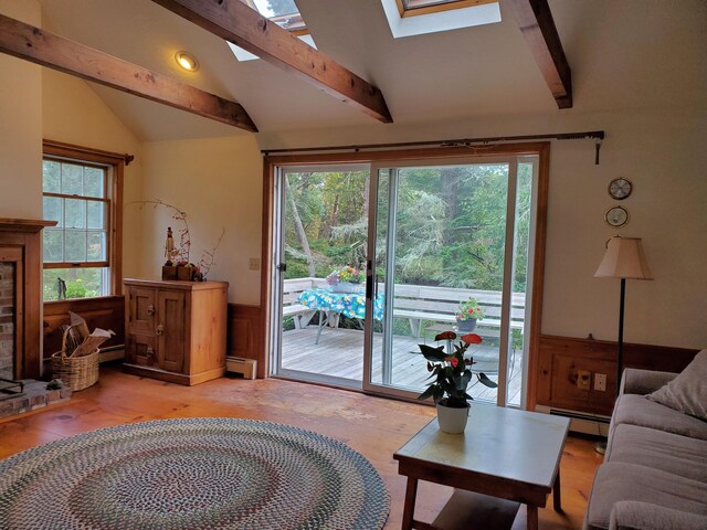 living room with lofted ceiling with skylight, plenty of natural light, and baseboard heating