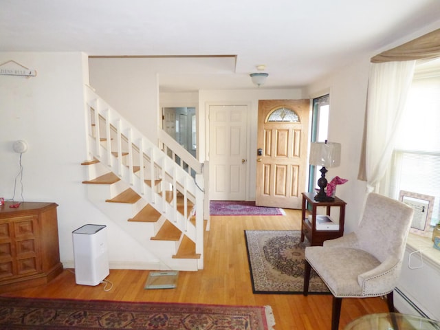 foyer entrance with wood-type flooring and a baseboard heating unit