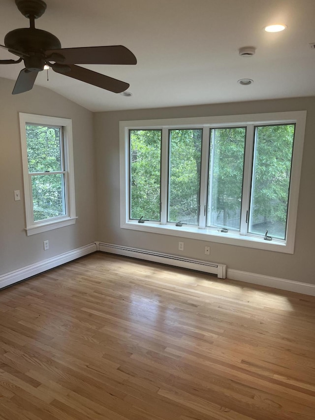 empty room with light hardwood / wood-style floors, vaulted ceiling, ceiling fan, and a baseboard radiator