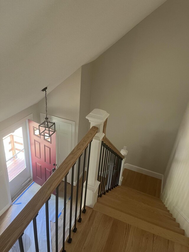 stairs with hardwood / wood-style floors and lofted ceiling