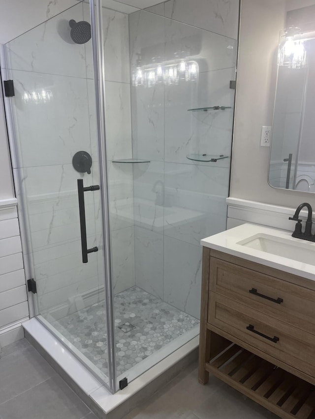 bathroom featuring a shower with shower door, vanity, and tile patterned flooring