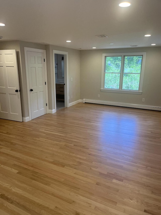 spare room with baseboard heating and light wood-type flooring