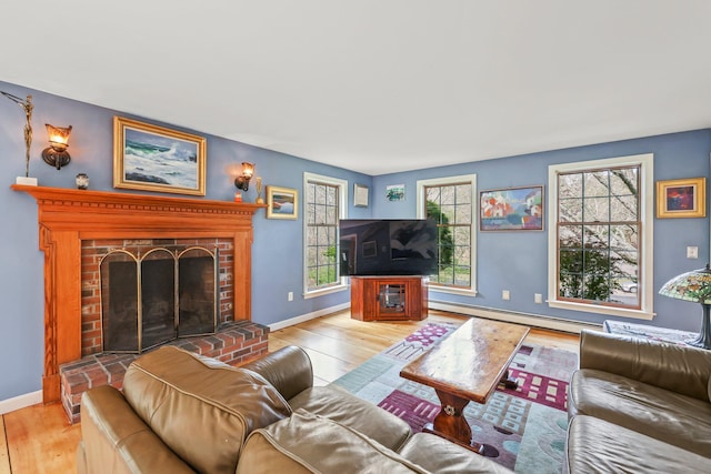 living room with a baseboard radiator, light hardwood / wood-style flooring, and a fireplace