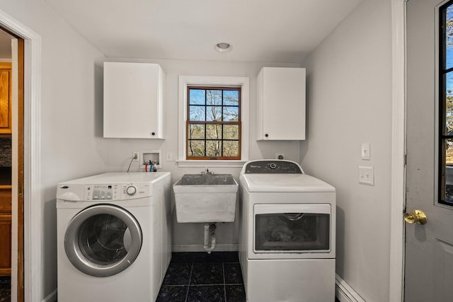 washroom with dark tile patterned flooring, cabinet space, a sink, washer and dryer, and baseboards