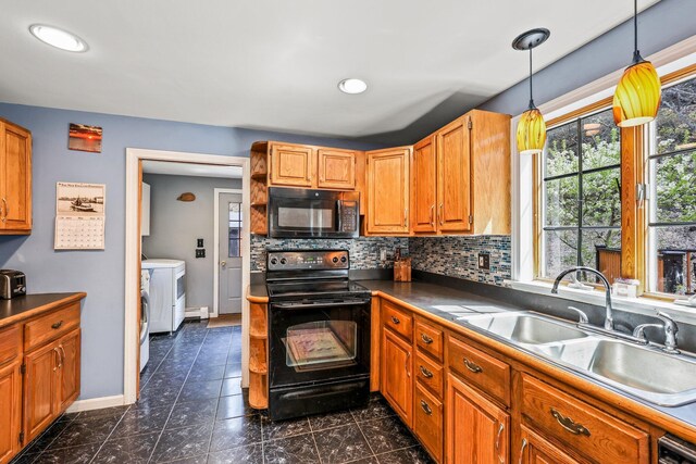 kitchen featuring a sink, baseboards, backsplash, black appliances, and washer and clothes dryer