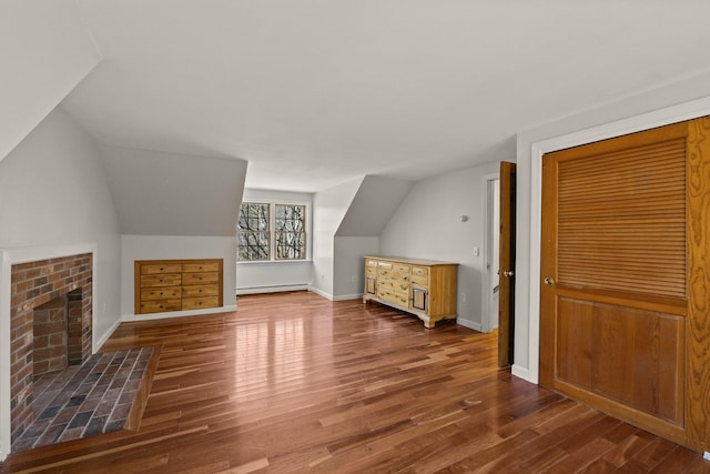 additional living space with a fireplace, baseboards, baseboard heating, and wood finished floors