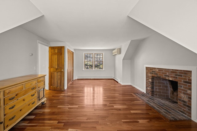 additional living space with baseboard heating, a fireplace, wood finished floors, and a wall mounted AC