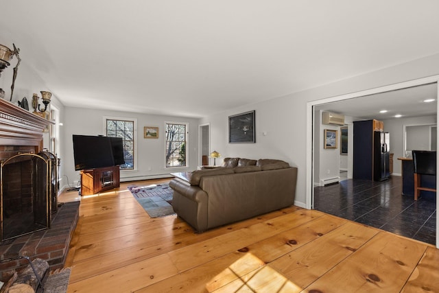 living room featuring baseboards, a wall unit AC, a baseboard radiator, hardwood / wood-style floors, and a fireplace