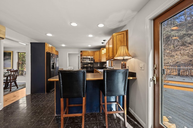 kitchen featuring recessed lighting, granite finish floor, black appliances, a peninsula, and baseboards