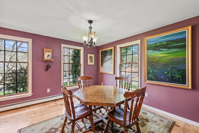 dining area with baseboard heating, hardwood / wood-style flooring, and an inviting chandelier