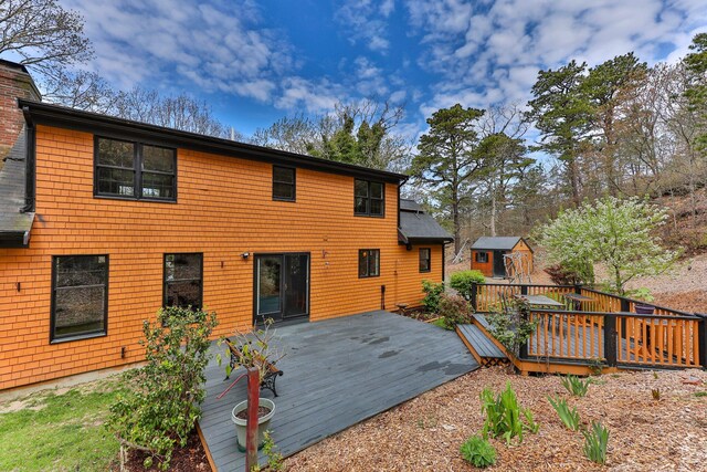 back of house featuring a storage unit, a deck, and an outbuilding