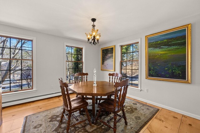 dining space with baseboards, baseboard heating, wood finished floors, and an inviting chandelier