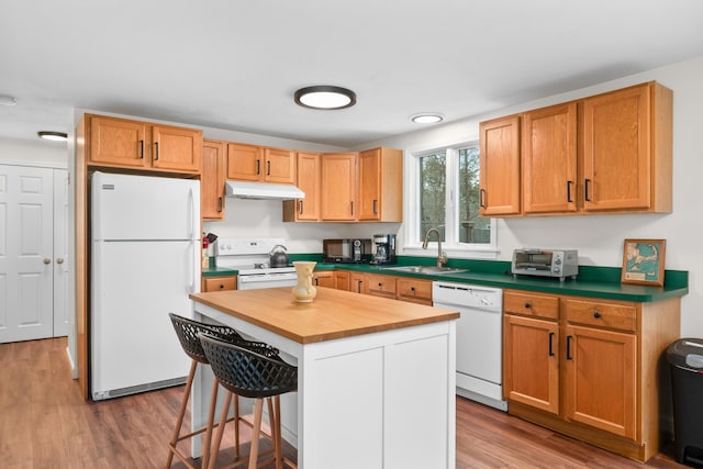 kitchen with wood finished floors, a sink, wood counters, white appliances, and under cabinet range hood