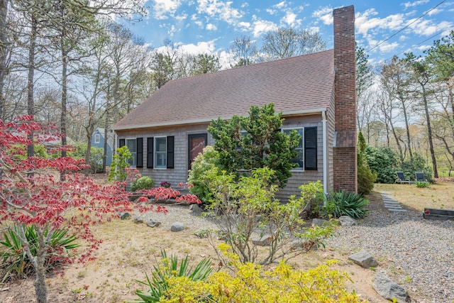 view of side of property with a shingled roof and a chimney