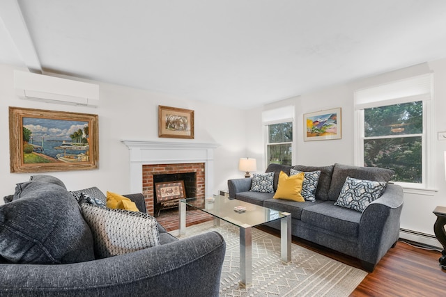 living room featuring a wall mounted air conditioner, wood finished floors, baseboard heating, and a brick fireplace