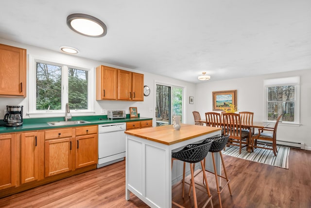 kitchen with a sink, a kitchen bar, light wood-type flooring, and dishwasher