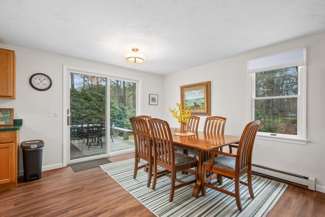 dining space featuring baseboards, baseboard heating, and wood finished floors