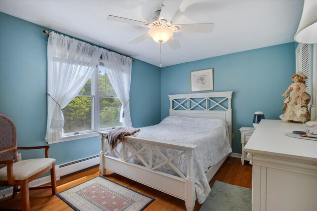bedroom featuring baseboard heating, wood finished floors, and ceiling fan