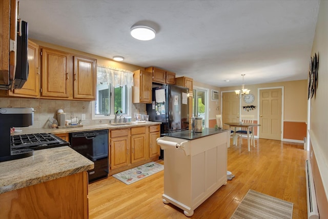 kitchen with black appliances, light wood-type flooring, a sink, and healthy amount of natural light