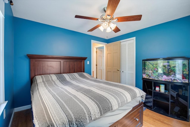 bedroom featuring a closet, light wood-style flooring, ceiling fan, and baseboards