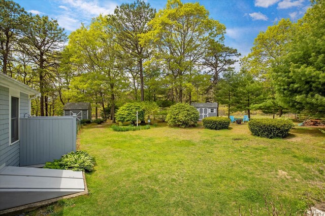 view of grassy yard featuring a storage unit, an outdoor structure, and view of scattered trees
