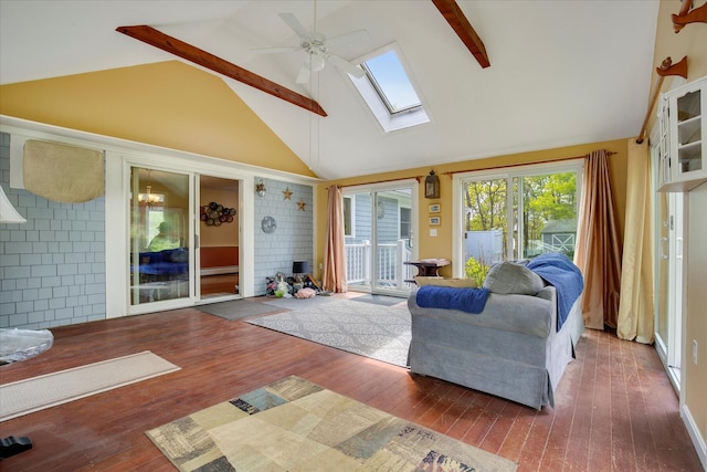 living room with a skylight, a ceiling fan, high vaulted ceiling, wood-type flooring, and a fireplace