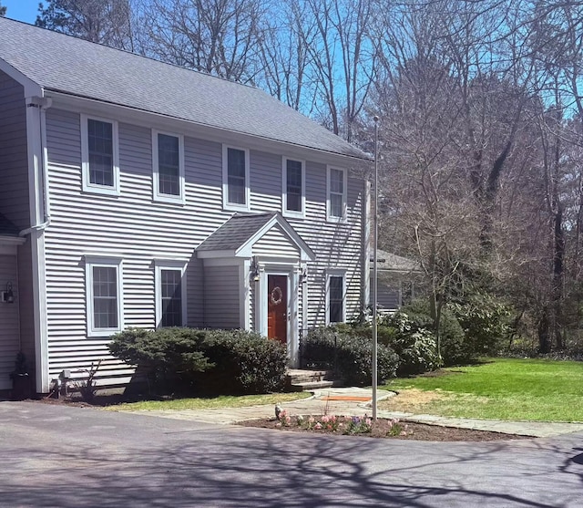 colonial-style house with a shingled roof and a front yard