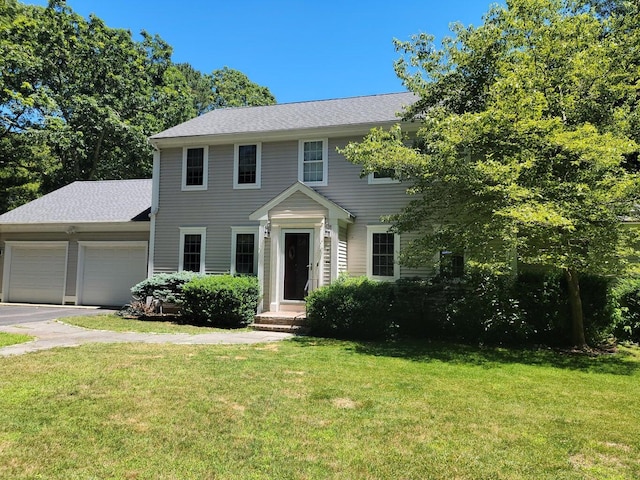 colonial inspired home featuring a garage and a front yard