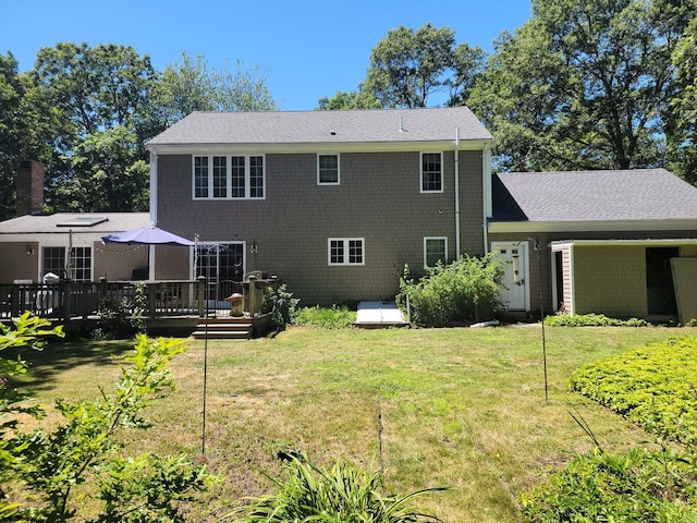 rear view of property with a wooden deck and a yard