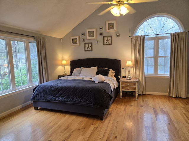 bedroom featuring baseboards, wood finished floors, multiple windows, and vaulted ceiling