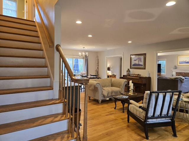 stairs featuring a fireplace, wood finished floors, recessed lighting, and a notable chandelier