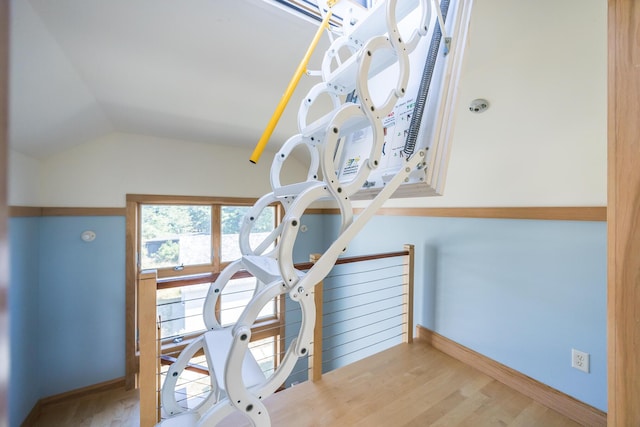 stairs featuring hardwood / wood-style floors and vaulted ceiling