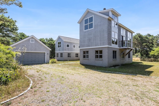 rear view of property with a balcony, a garage, a yard, and an outdoor structure