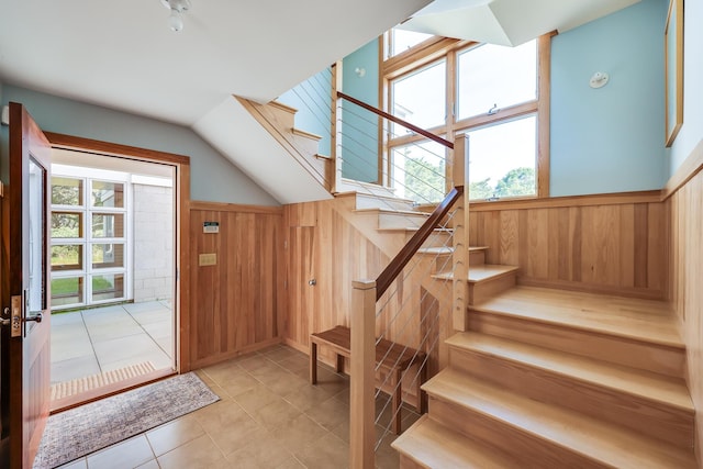 entryway with wood walls and light tile patterned floors