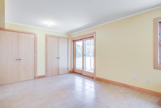 unfurnished bedroom featuring two closets, access to exterior, ornamental molding, and light tile patterned flooring