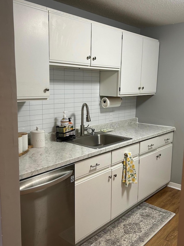 kitchen featuring dark wood-type flooring, sink, dishwasher, white cabinets, and backsplash