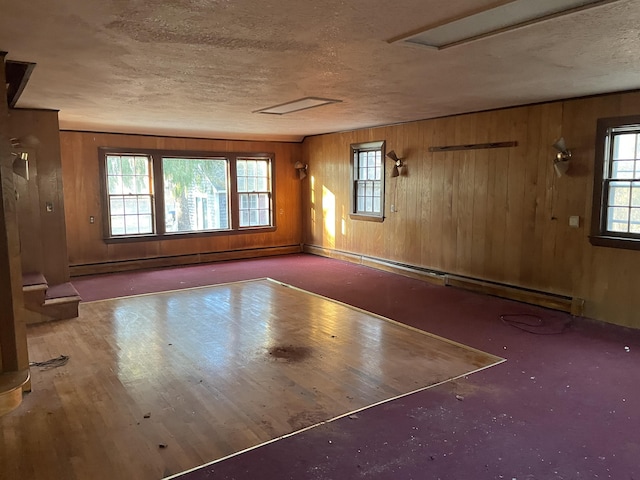 unfurnished room with wooden walls and a baseboard heating unit