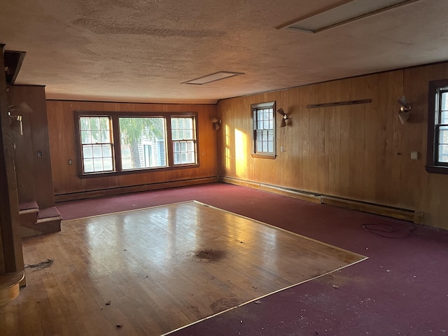 interior space with wood walls, a baseboard heating unit, and a textured ceiling