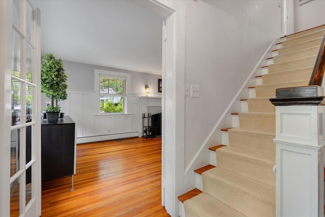 117 Parker Rd, Osterville, MA 02655 - staircase with a baseboard radiator, wood finished floors, wainscoting, and a decorative wall