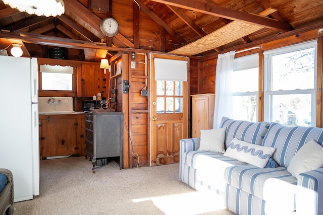 carpeted living room with wood walls, sink, lofted ceiling with beams, and wood ceiling