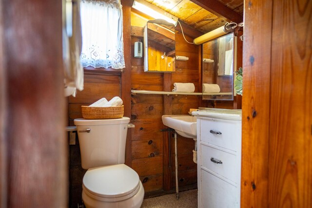 bathroom featuring wooden ceiling, wooden walls, beamed ceiling, and toilet