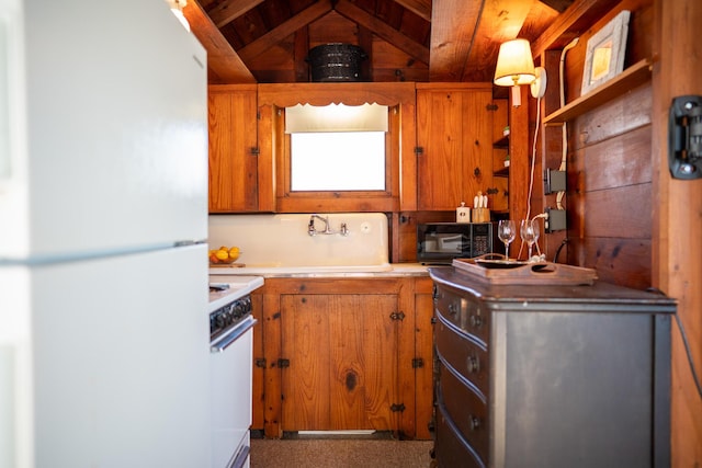 kitchen with sink, lofted ceiling with beams, range, wood walls, and white fridge