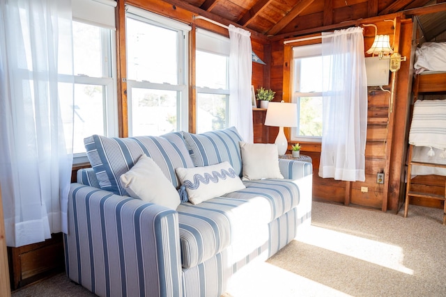 interior space featuring carpet, wooden walls, wood ceiling, and vaulted ceiling with beams