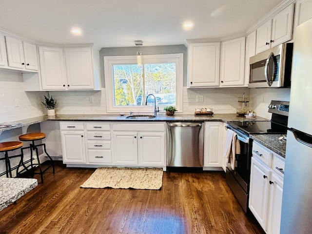 kitchen featuring a sink, dark wood-style flooring, white cabinetry, stainless steel appliances, and backsplash