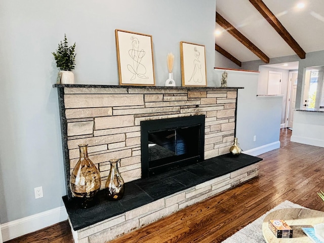 interior details with wood finished floors, baseboards, beam ceiling, and a stone fireplace
