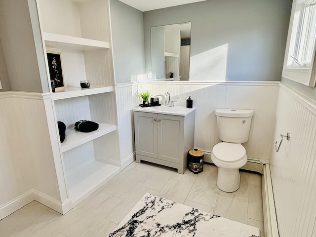 bathroom featuring vanity, toilet, a baseboard heating unit, wainscoting, and a baseboard radiator
