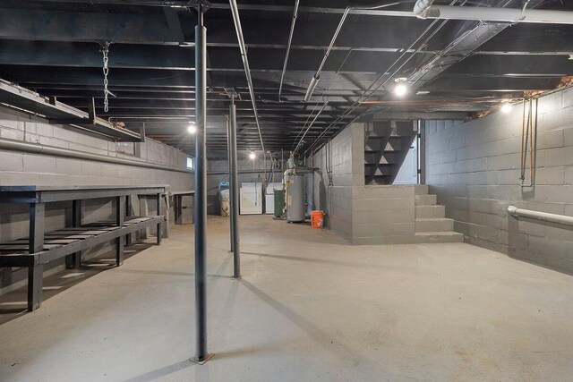 unfinished below grade area featuring washer / clothes dryer, stairs, and gas water heater