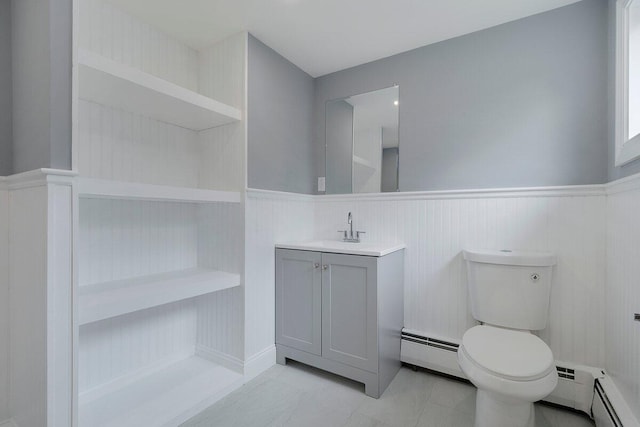 bathroom with toilet, vanity, a baseboard radiator, and a wainscoted wall